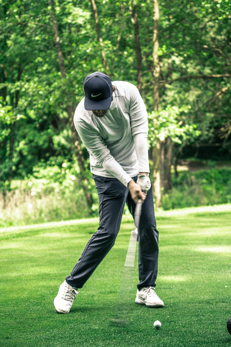 golfer swinging golf club at ball on ground