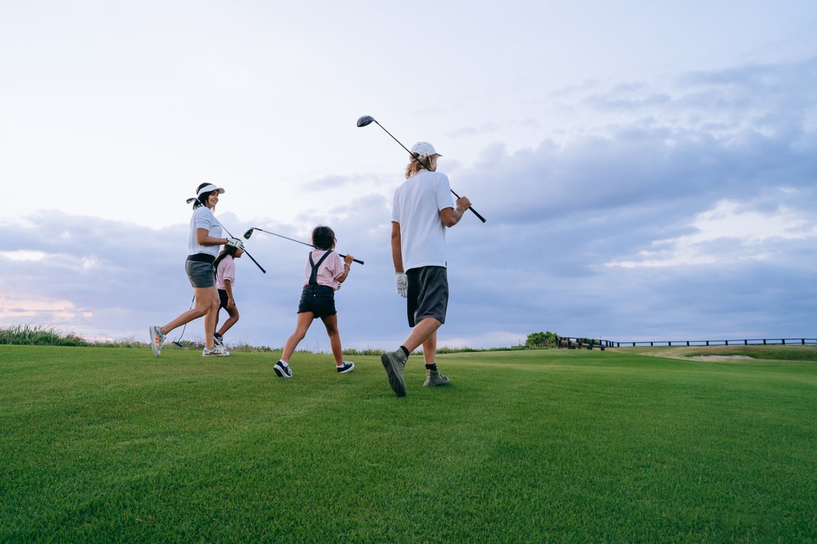 a group of people, adults and children, walking on a golf course